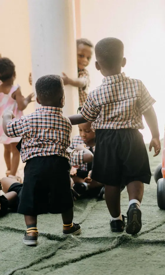 Small children in checked uniforms playing together in a nursery classroom in Accra, Ghana.