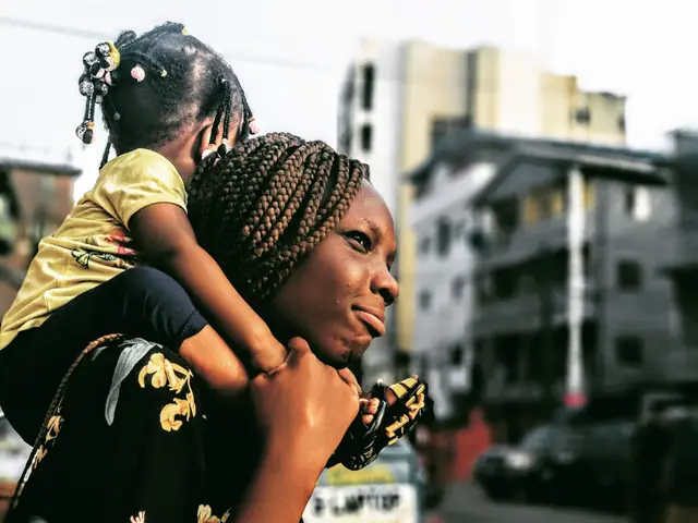 A mother carrying her young daughter on her shoulders on a city street in Lagos, Nigeria.