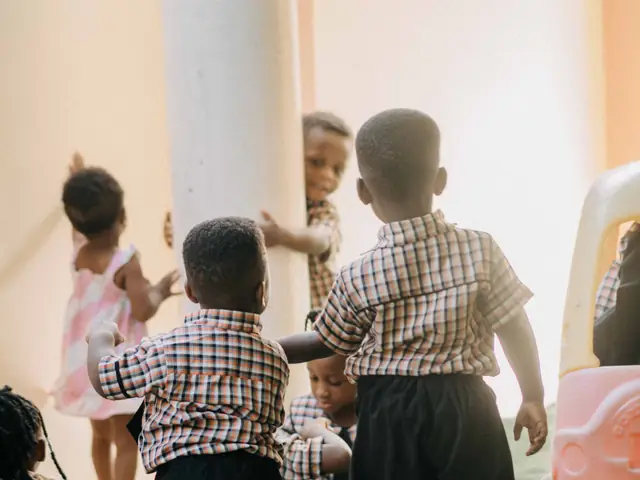 Small children in checked uniforms playing together in a nursery classroom in Accra, Ghana.