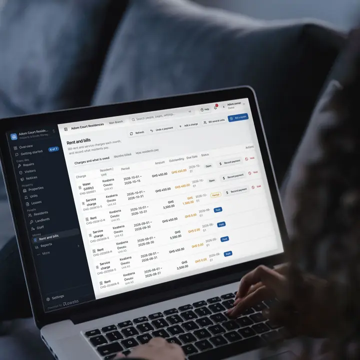 A woman on a sofa working on a laptop that shows an estate's Rent and bills in Rowsta: rent, service charge and water for a resident, with what is still owed.