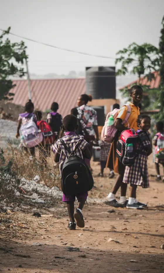 Children with school bags walking home together in Accra.